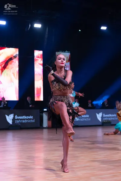Dancesport competitor: Female dancer in foreground: bronze-colored sequined Latin dress with a fringed 