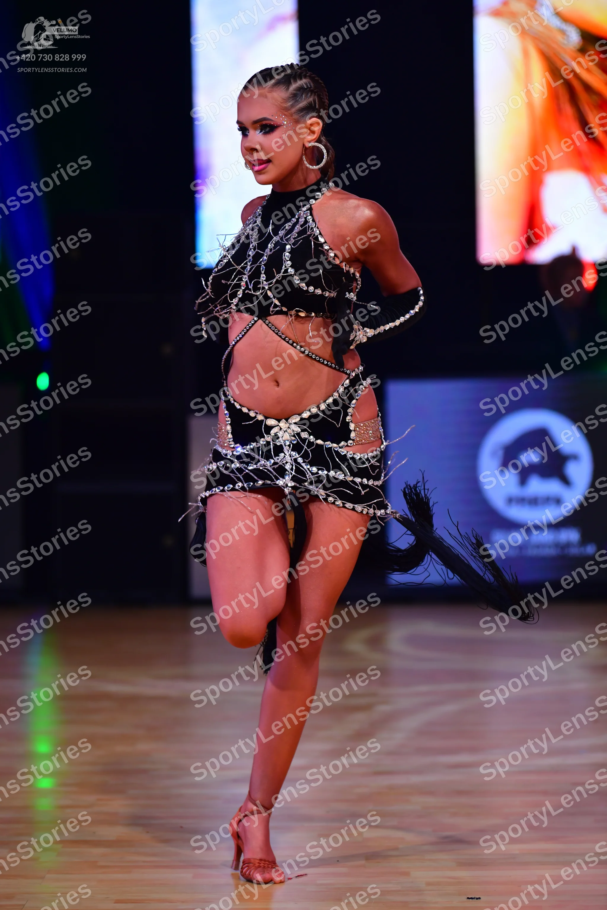 Dancesport competitor: Female dancer: black latin dance costume with cutout details, heavily embellishe