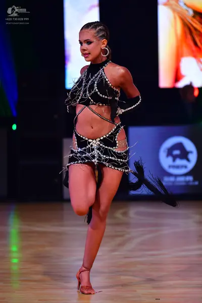 Dancesport competitor: Female dancer: black latin dance costume with cutout details, heavily embellishe