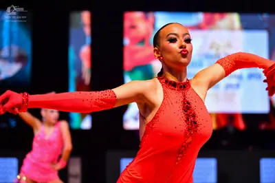 Dancesport competitor: Female dancer in foreground: red latin dress with sequin/beaded embellishments a