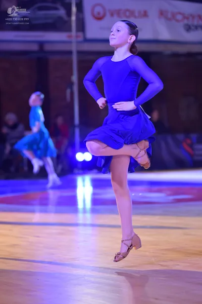 Dancesport competitor: Female dancer in foreground: blue long-sleeved dance dress with a short skirt