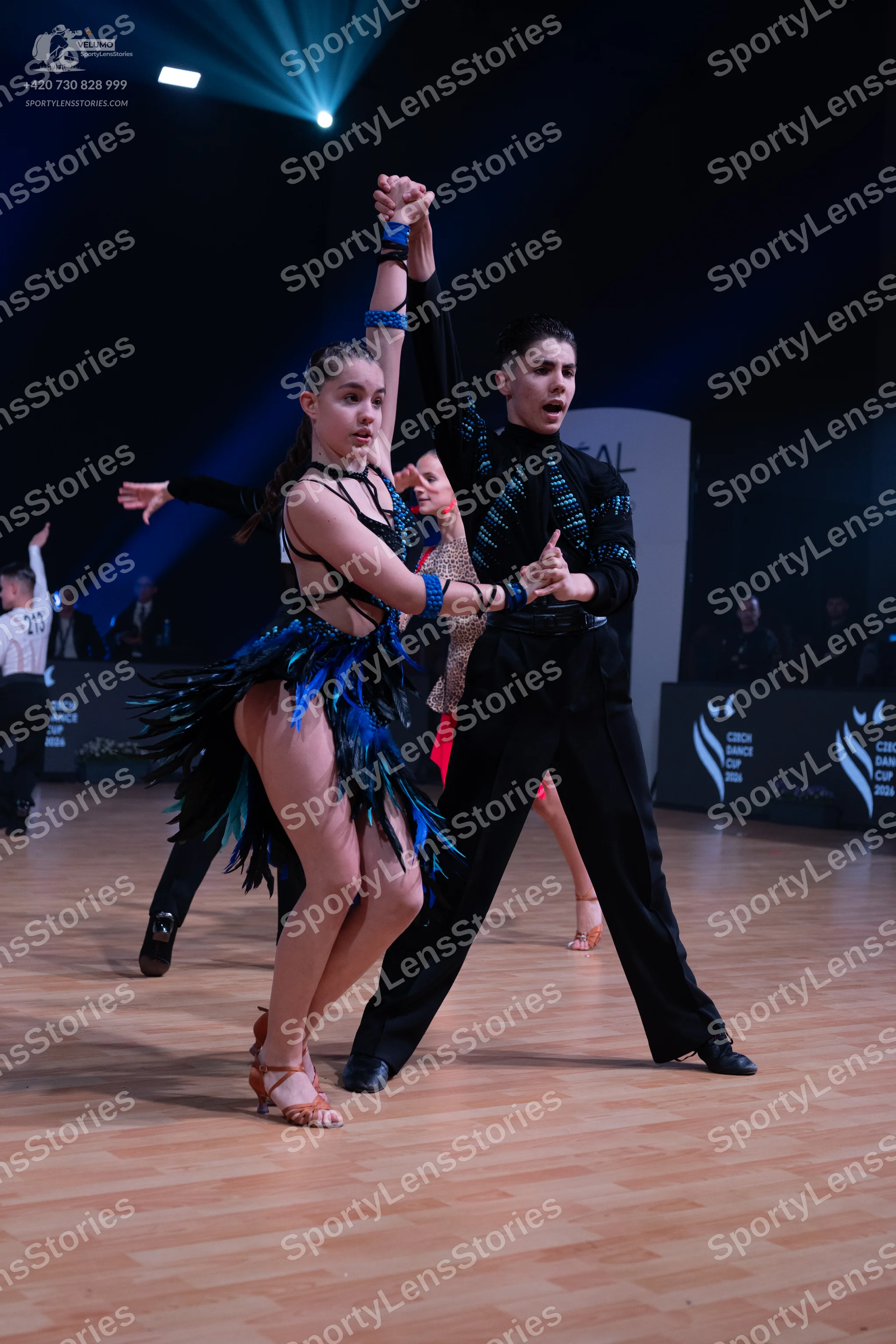 Dancesport competitor: Female dancer: black Latin dance dress with blue and green sequins and fringe
