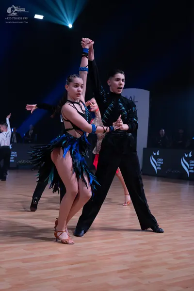 Dancesport competitor: Female dancer: black Latin dance dress with blue and green sequins and fringe