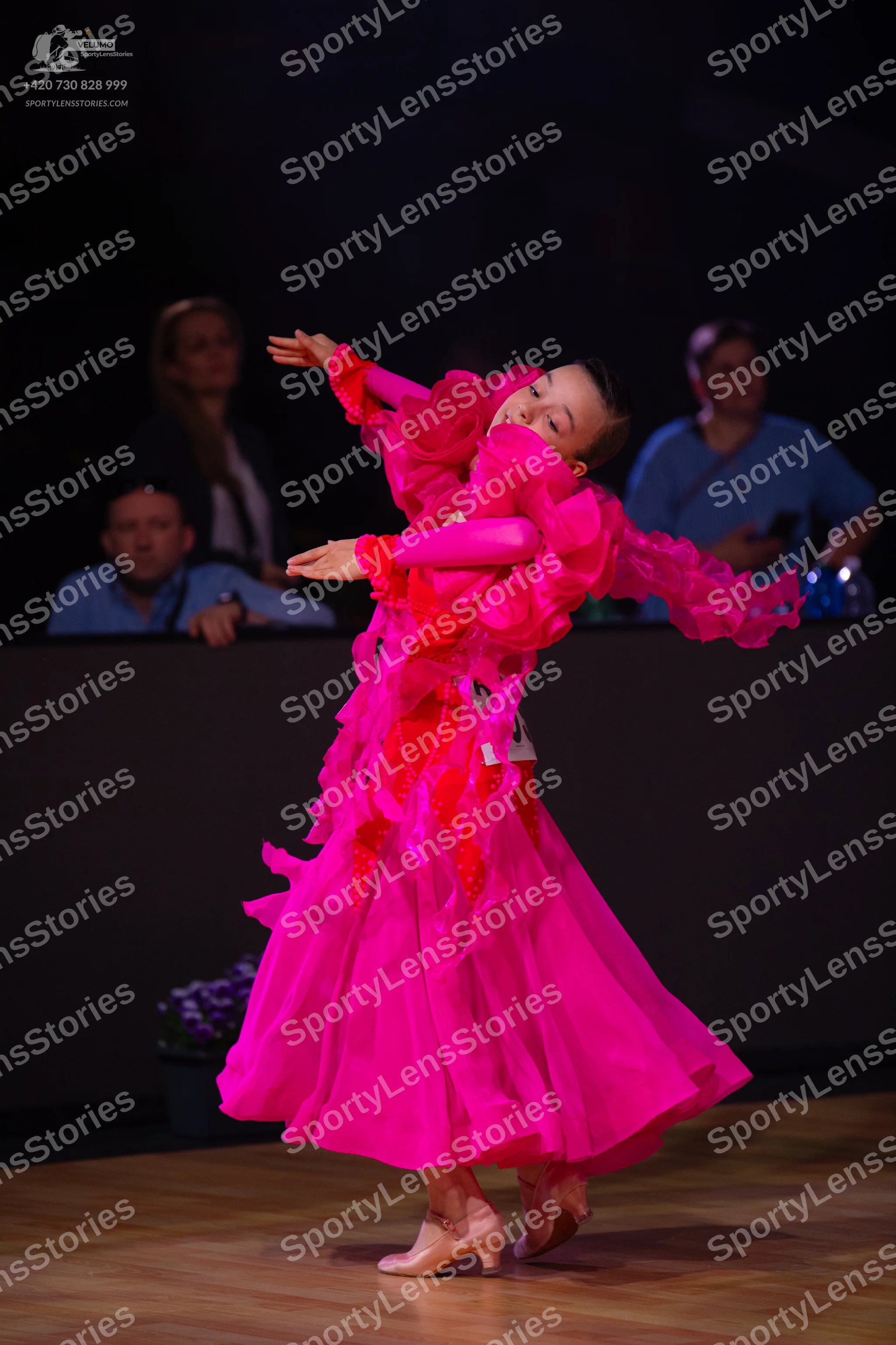 Dancesport competitor: Female dancer: bright pink ballgown with voluminous ruffled layers of fabric and