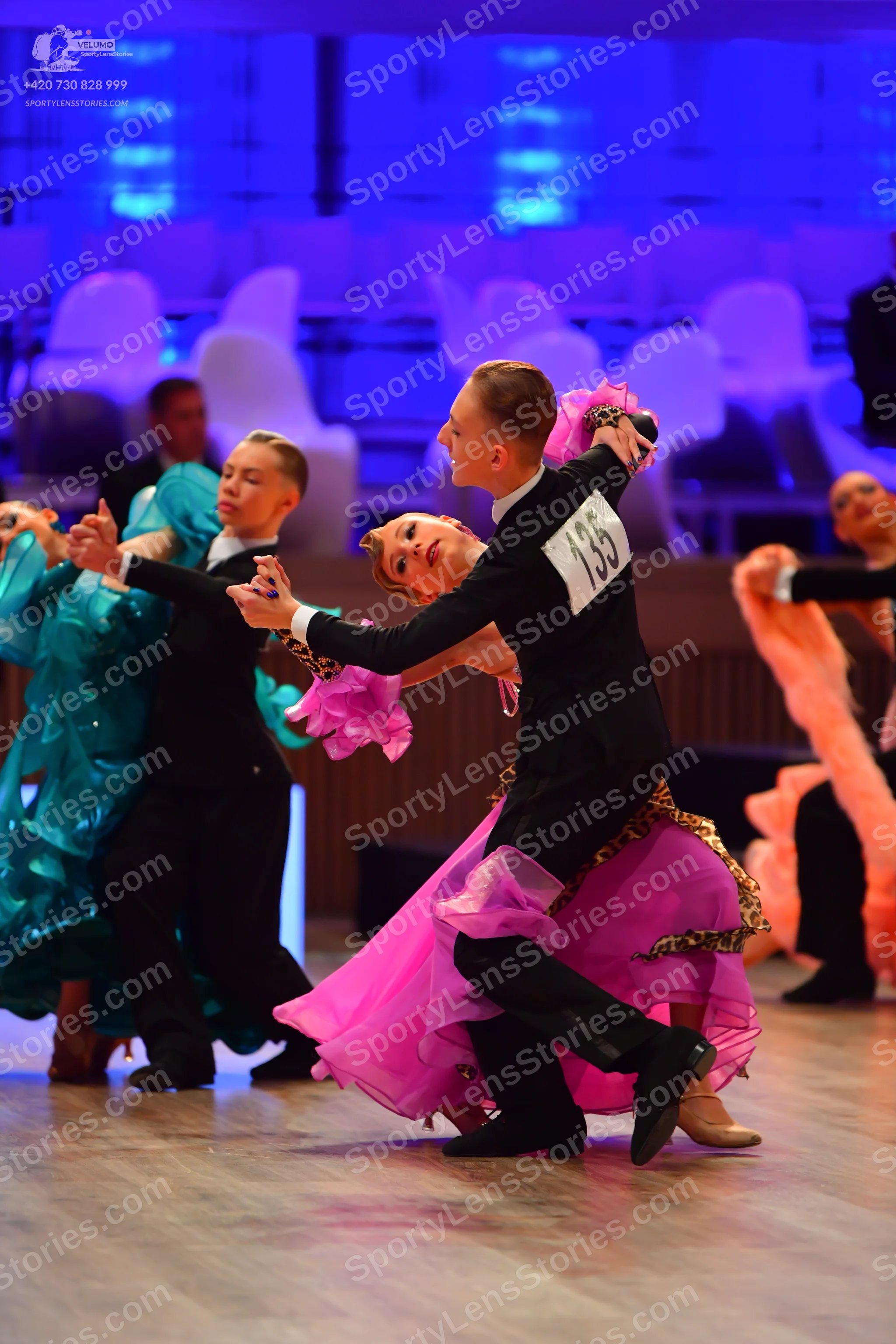 Dancesport competitor: Male dancer in foreground: black long-sleeved shirt and black trousers