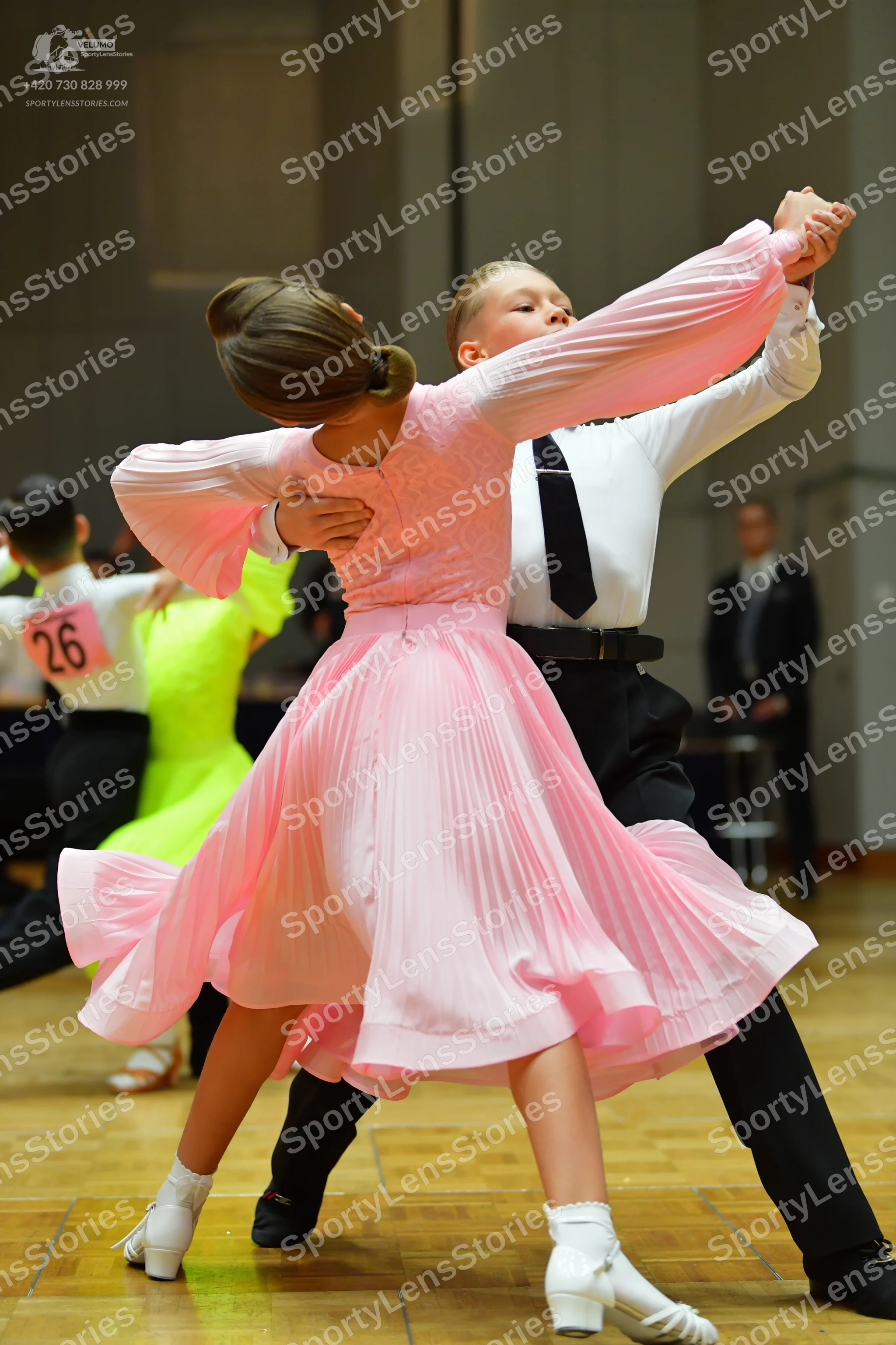 Dancesport competitor #26: Foreground female dancer: light pink, long-sleeved, pleated flowing skirt