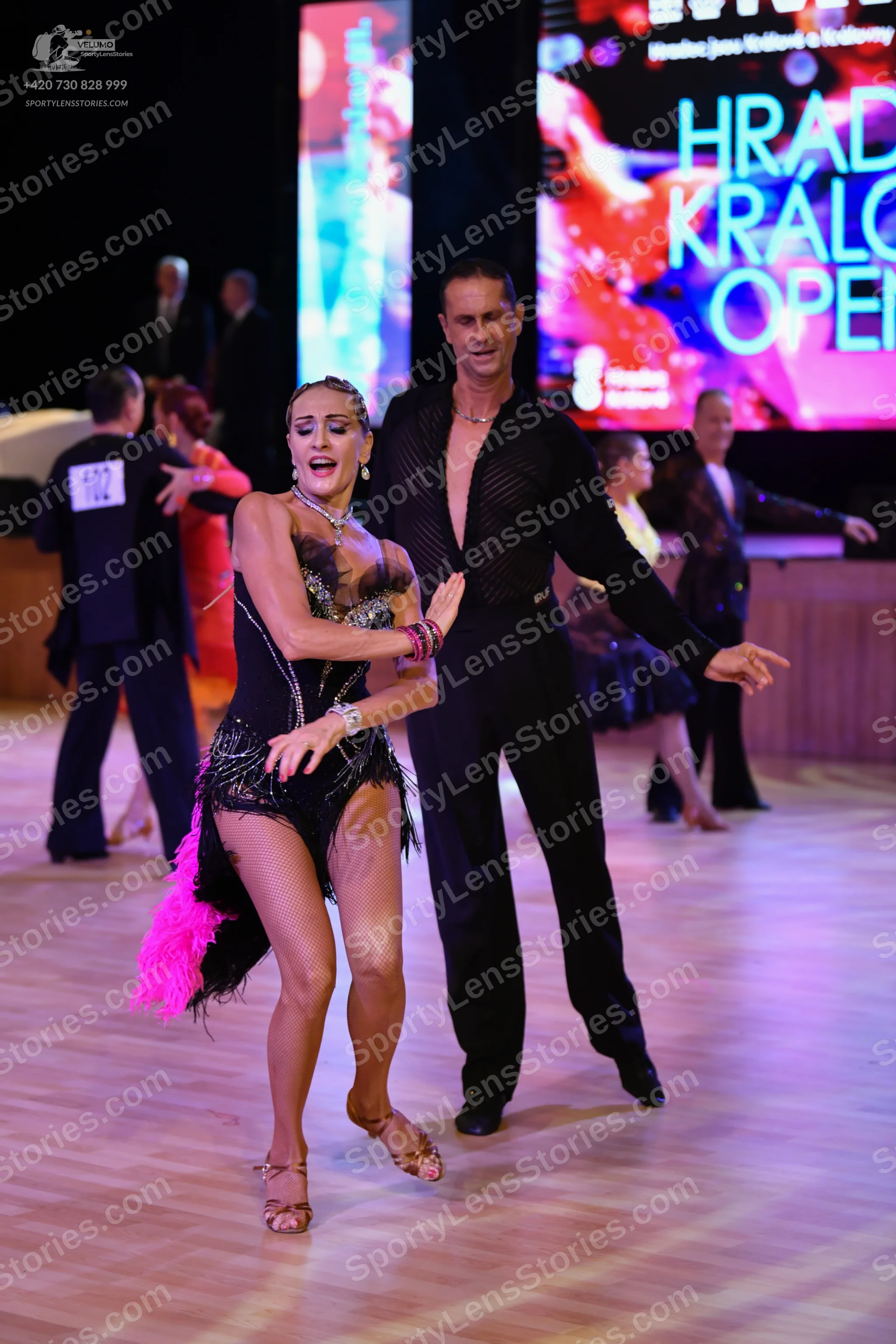 Dancesport competitor: Okay, here's a breakdown of the dancers' costumes in the photo, as requested:

*