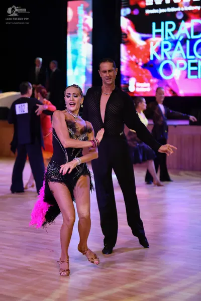 Dancesport competitor: Okay, here's a breakdown of the dancers' costumes in the photo, as requested:

*
