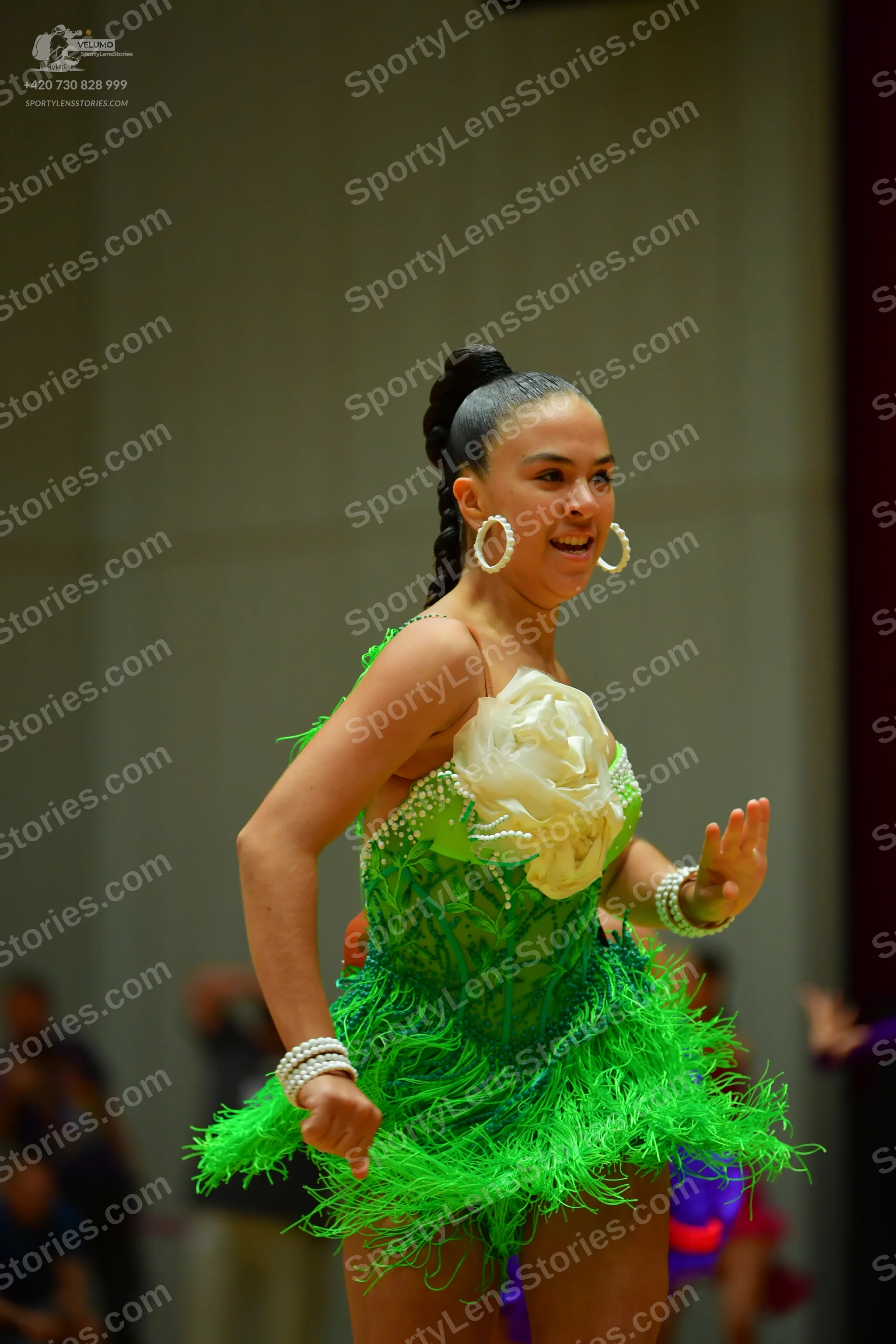 Dancesport competitor: Female dancer: bright green Latin dance dress with long fringe and a large cream