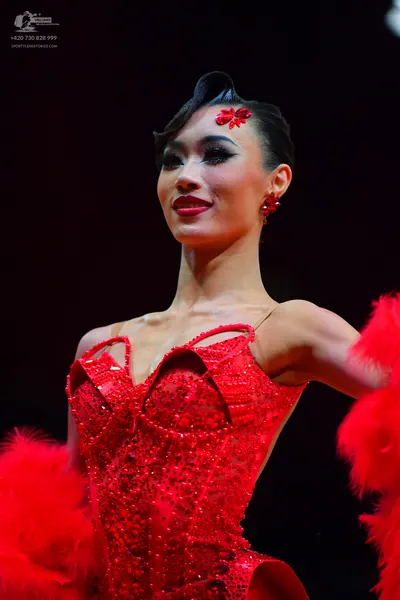 Dancesport competitor: Female dancer: red latin dress with sequins and red feather trim, accessorized w