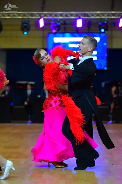 Dancesport competitor: Female dancer: bright pink/magenta Latin dress with a red, heavily textured bodi