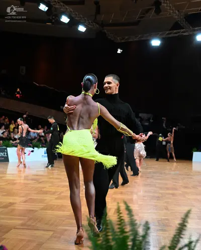 Dancesport competitor: Foreground female dancer: yellow latin dress with fringe