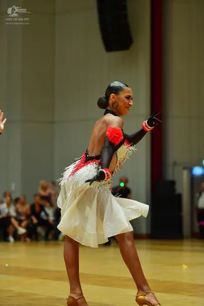 Dancesport competitor: Female dancer: black and white latin dress with red floral and fringe details, l