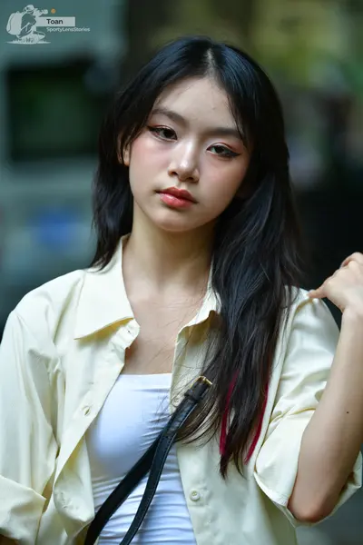 Dancesport competitor: The person is wearing a cream-colored button-up shirt over a white tank top