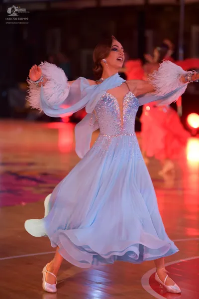 Dancesport competitor: Female dancer in foreground: light blue ballroom dress with a sequined bodice an