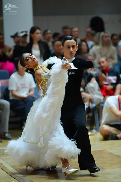 Dancesport competitor: Female dancer: voluminous white ballroom gown with feather-like textures and gol