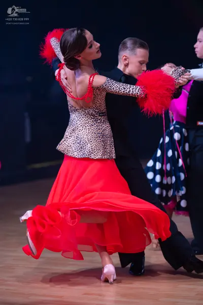 Dancesport competitor: Female dancer: leopard print long-sleeved top with large red feathery accents on