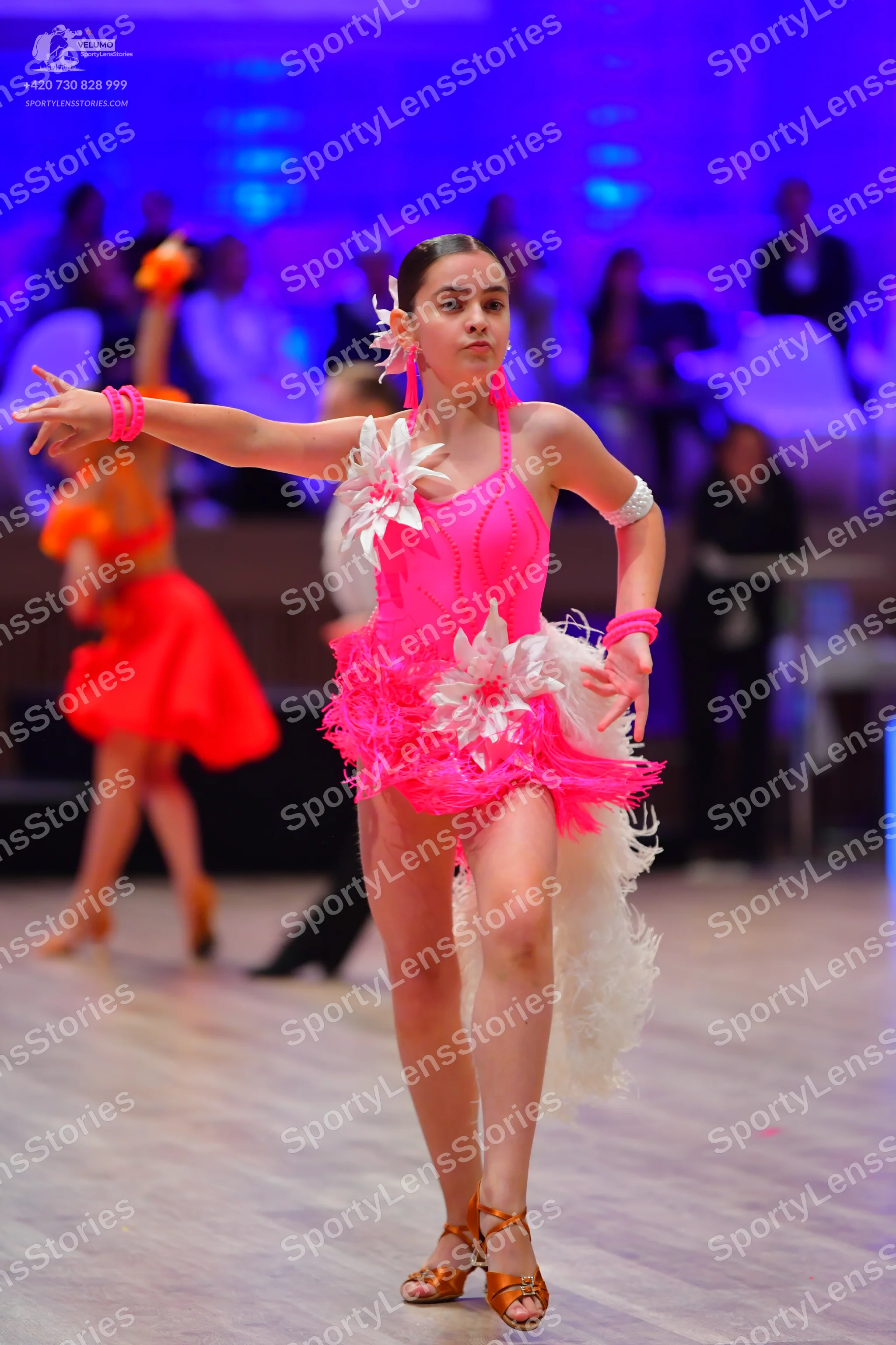 Dancesport competitor: Main female dancer: bright pink latin dress with white floral embellishments and