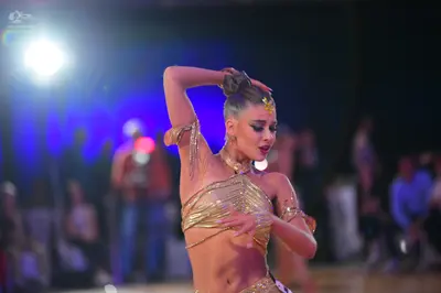 Dancesport competitor: Female dancer: gold, two-piece latin dance costume made of shimmering/sequined f