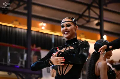 Dancesport competitor: Main female dancer: black, long-sleeved, Latin-style costume with strappy cut-ou