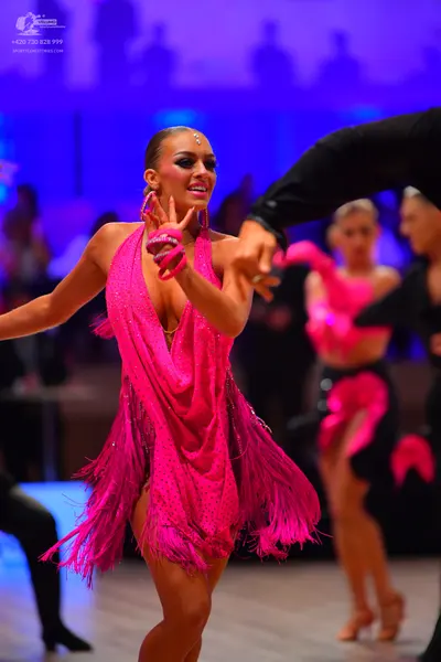 Dancesport competitor: Main female dancer: hot pink Latin dance dress with sequins and long fringe, fea