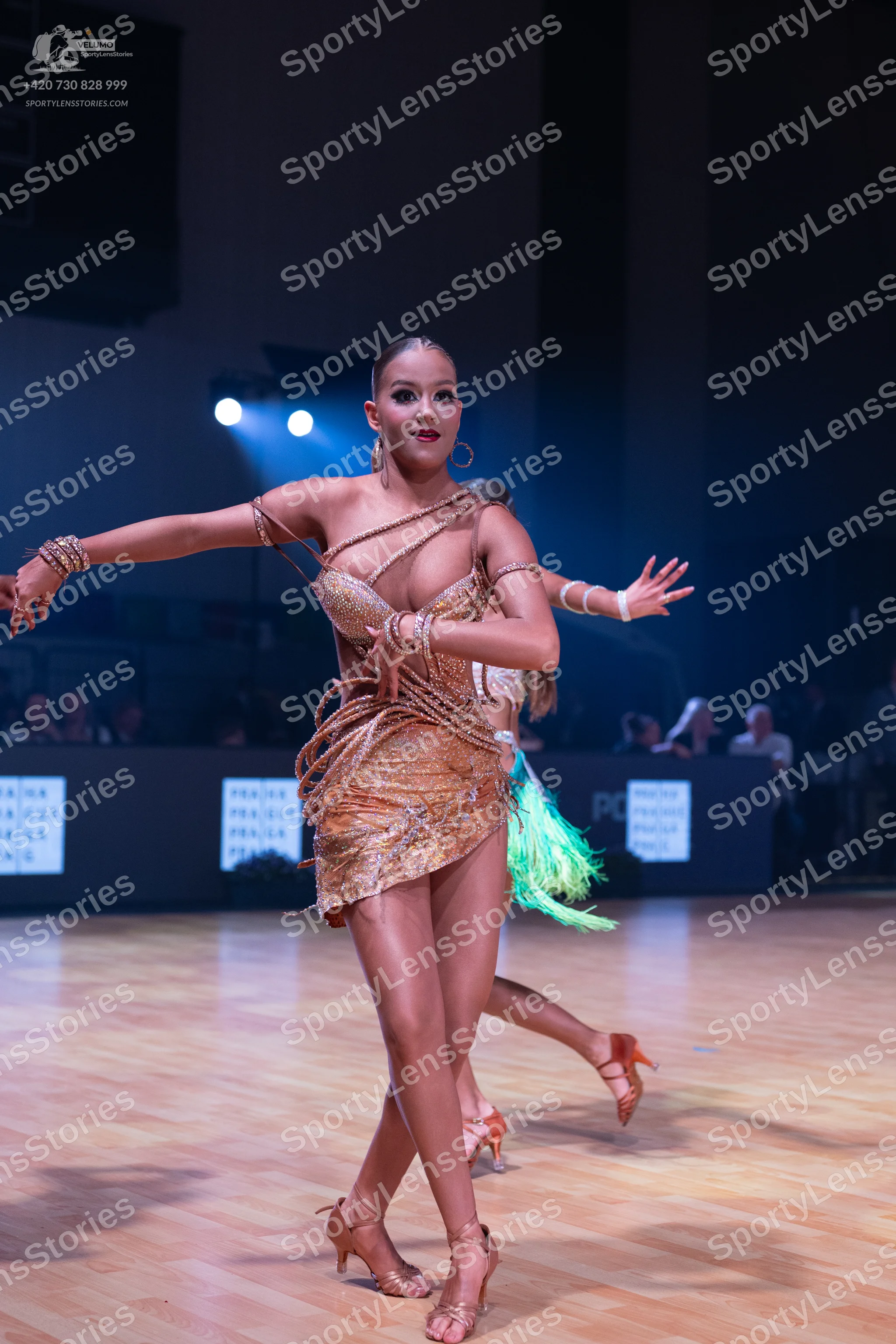 Dancesport competitor: Female dancer: gold/bronze sequined Latin dress with asymmetrical straps and gre