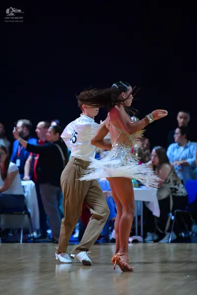 Dancesport competitor: Male dancer: white short-sleeved shirt, tan trousers, and white dance shoes