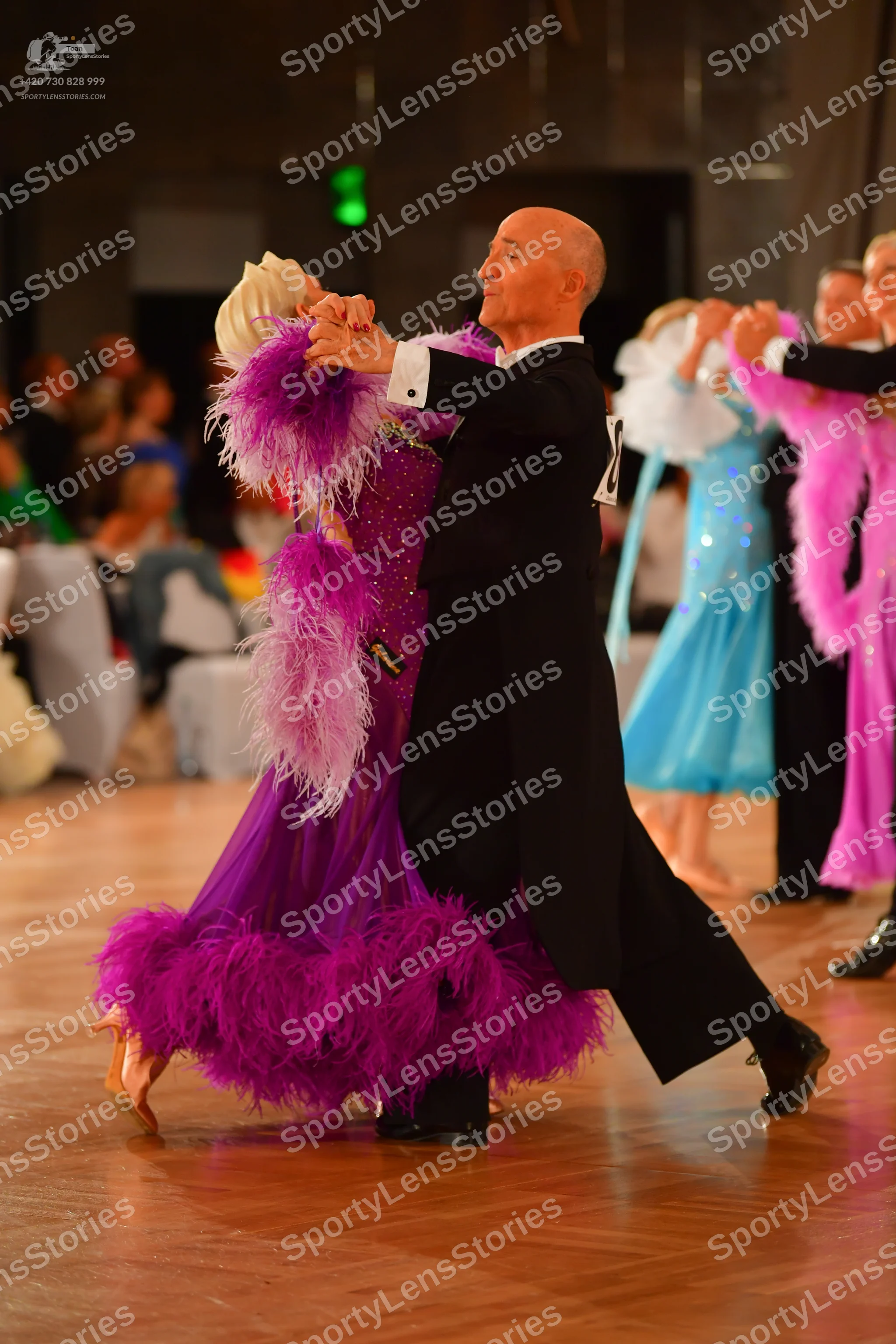 Dancesport competitor: Main female dancer: magenta Latin dress with heavy feather trim on the sleeves a