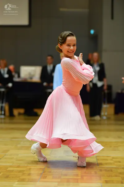 Dancesport competitor: Female dancer: light pink long-sleeved ballroom dress with a pleated bodice and 