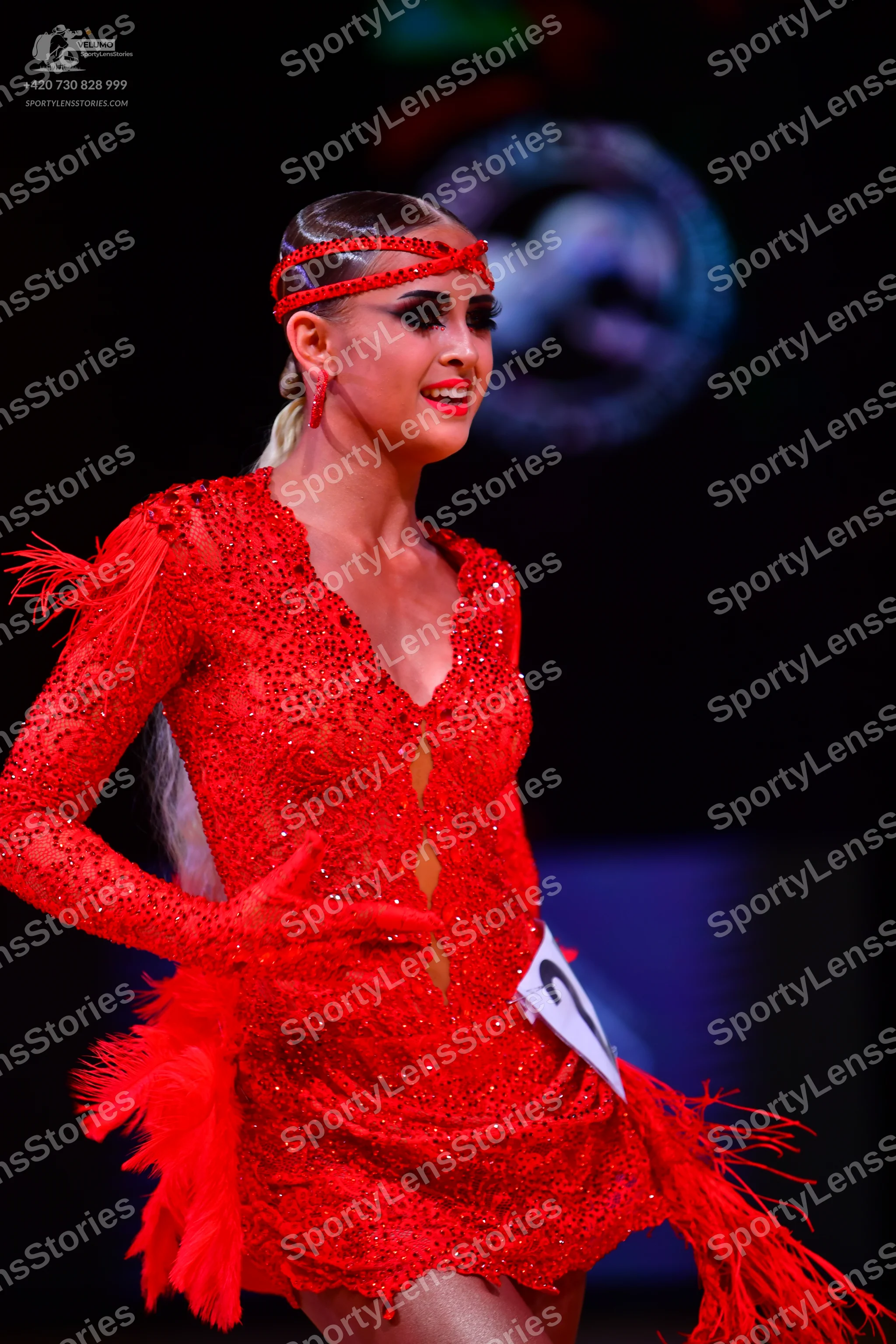 Dancesport competitor: Female dancer: red latin dress with sequins, long sleeves, deep V-neck, and frin