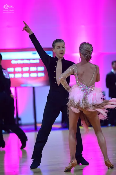 Dancesport competitor: Male dancer: black long-sleeve top with a small light-colored button detail and 