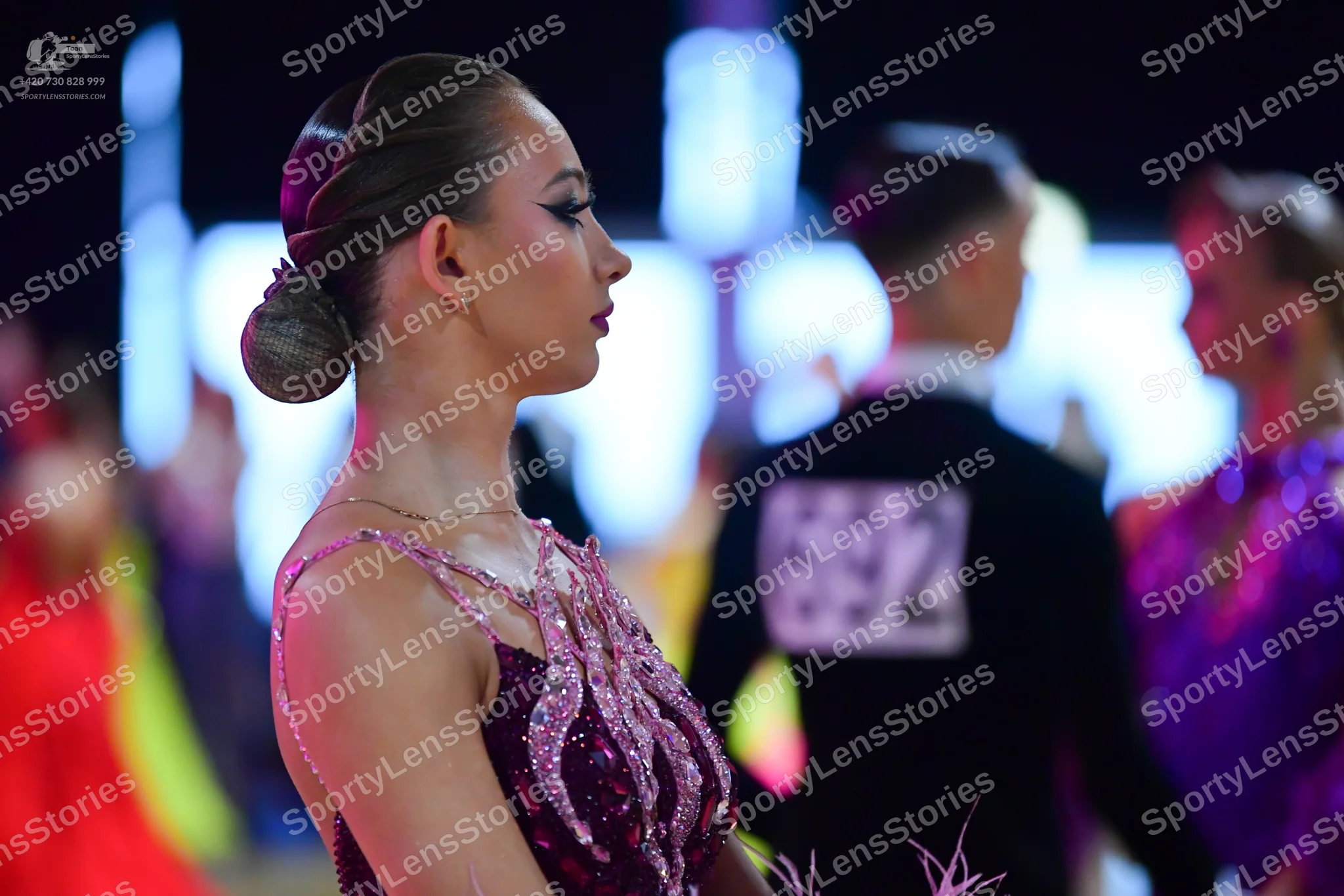 Dancesport competitor #692: Female dancer in foreground: maroon Latin dress with intricate, light-colored se