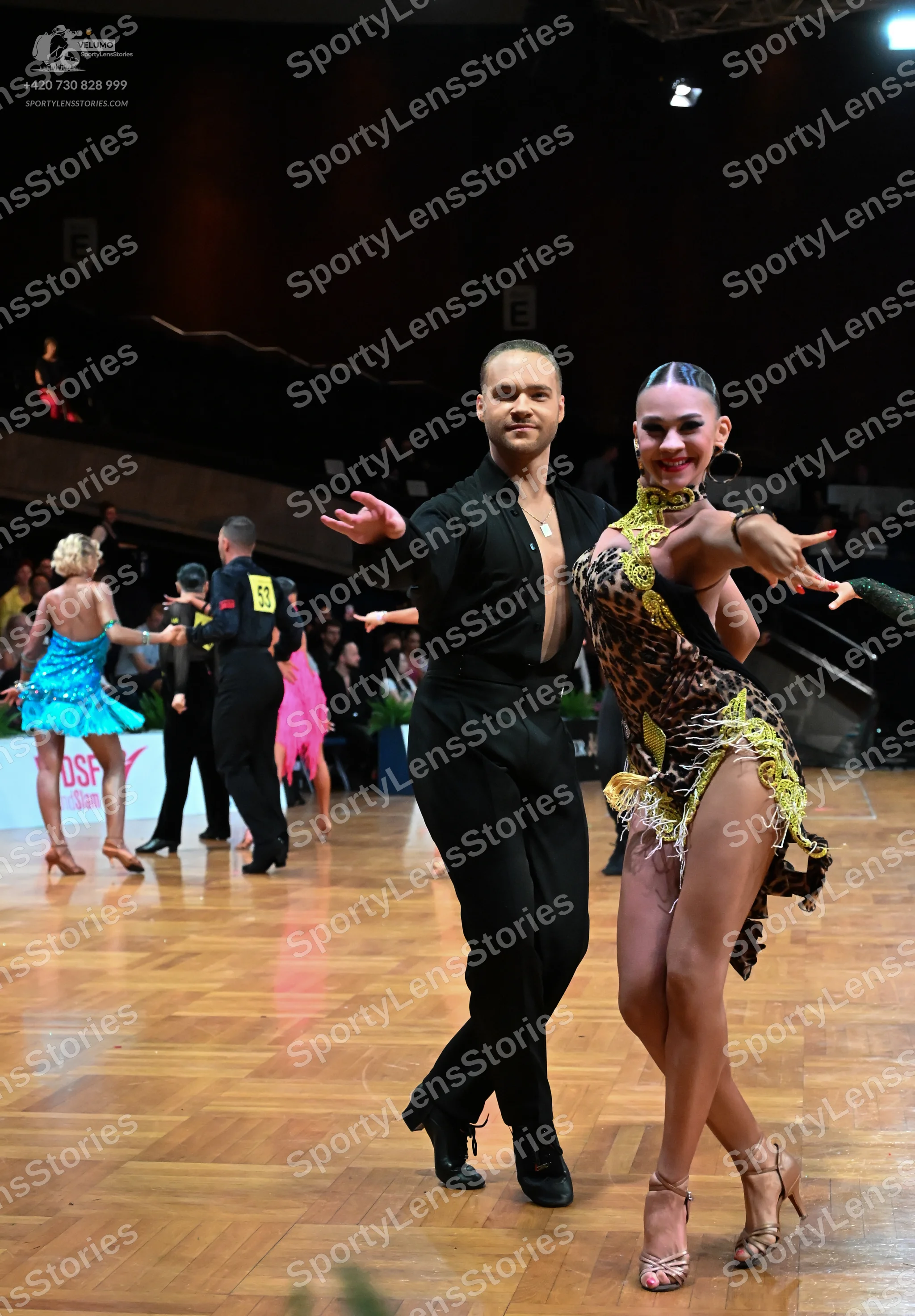 Dancesport competitor: Male dancer in foreground: black long-sleeved shirt and black trousers