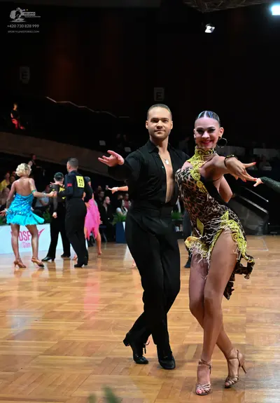 Dancesport competitor: Male dancer in foreground: black long-sleeved shirt and black trousers