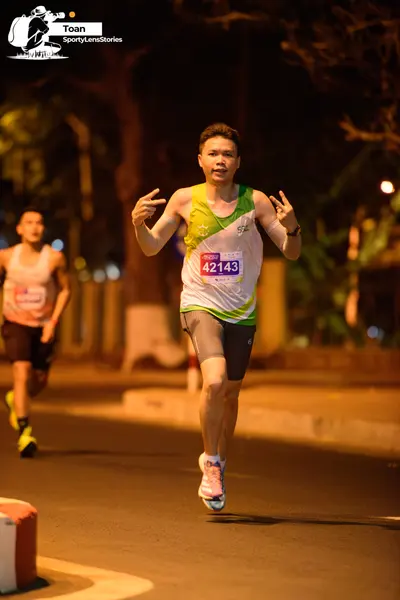 Marathon runner #42143: Runner 1: white and green jersey, black shorts, white and pink shoes, black watc
