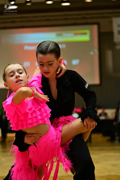 Dancesport competitor: Female dancer: bright pink latin dance dress with a ruffled top and long pink fr