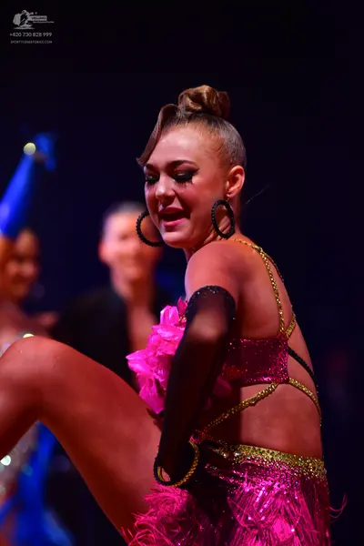 Dancesport competitor: Female dancer: pink Latin dance costume with sequins, fringe, and gold sequined 