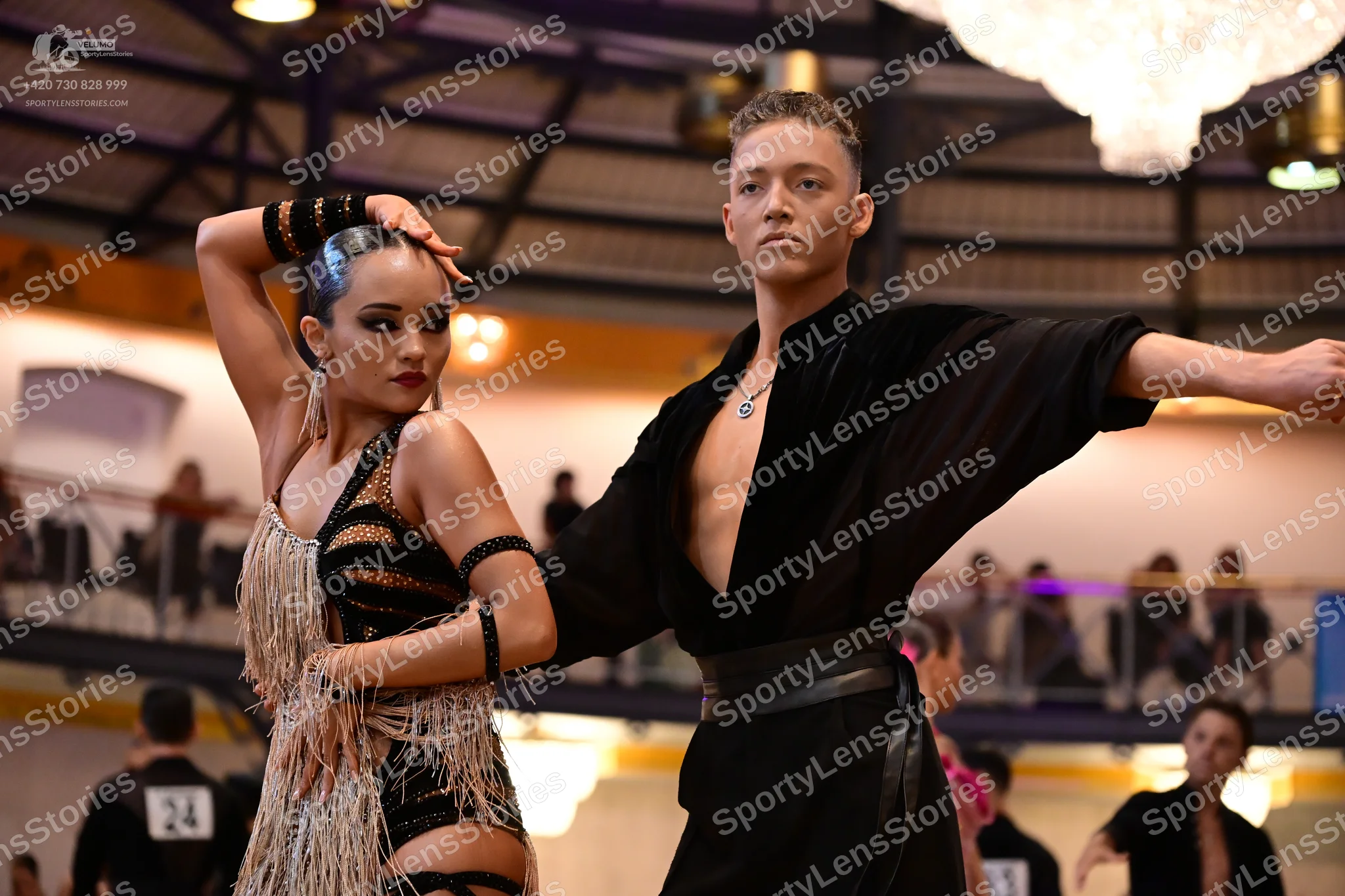 Dancesport competitor #24: Female dancer: black latin dress with gold sequin patterns and long fringe, with