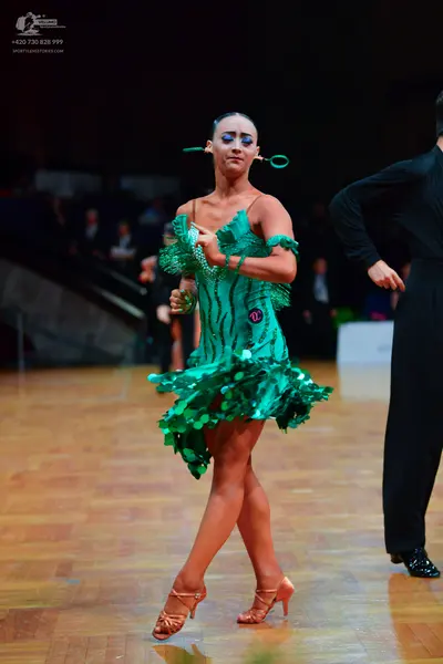 Dancesport competitor: Female dancer: green Latin dress featuring large, shimmering green sequins and a