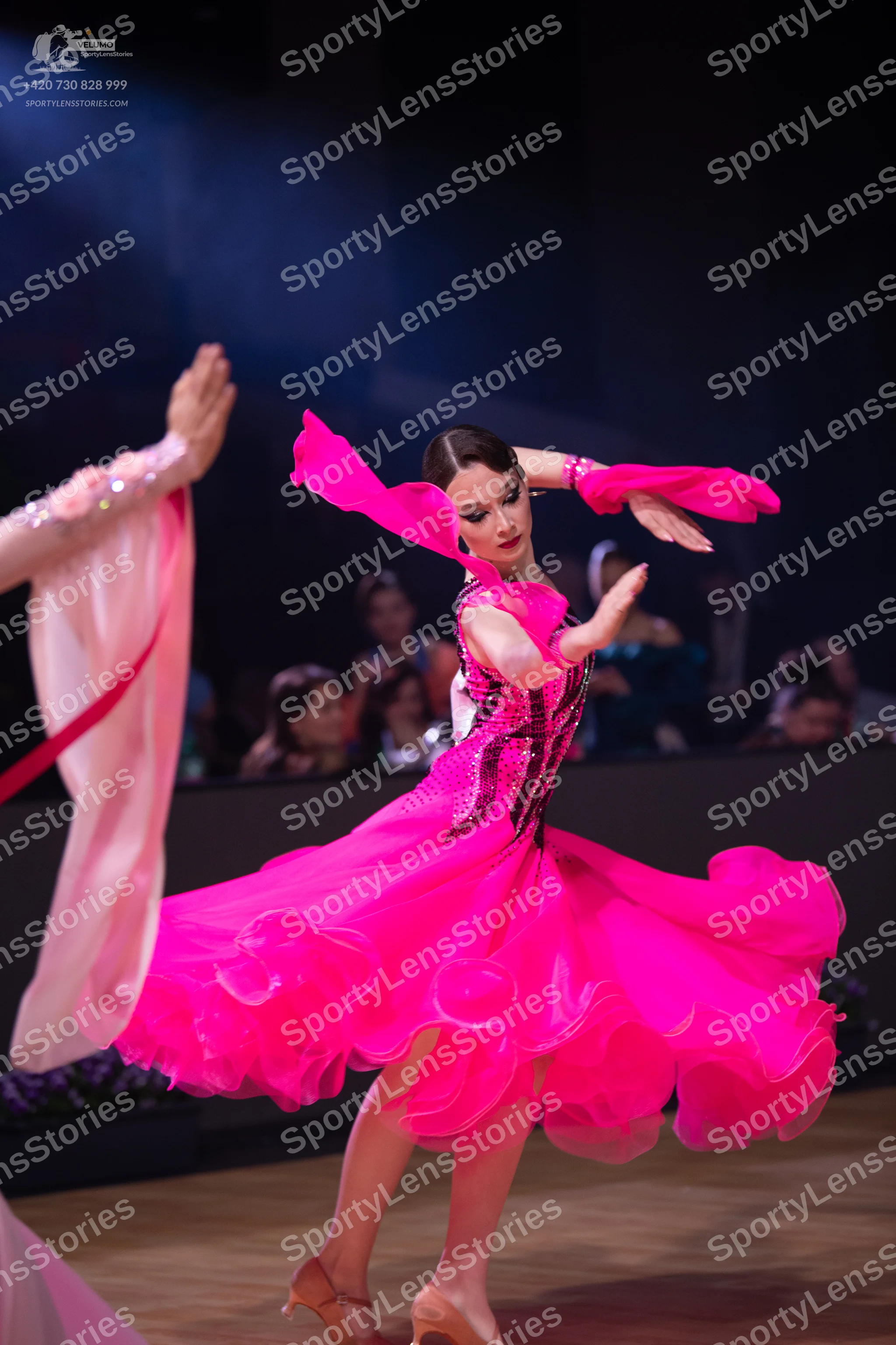 Dancesport competitor: Female dancer: bright pink ballroom dress with a voluminous, ruffled skirt, a bo