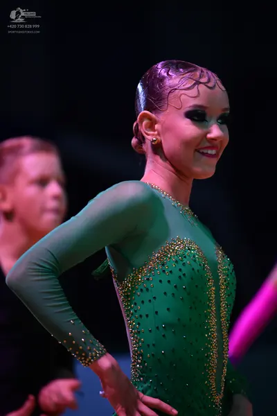Dancesport competitor: Female dancer: green long-sleeved latin dance dress with gold sequin embellishme