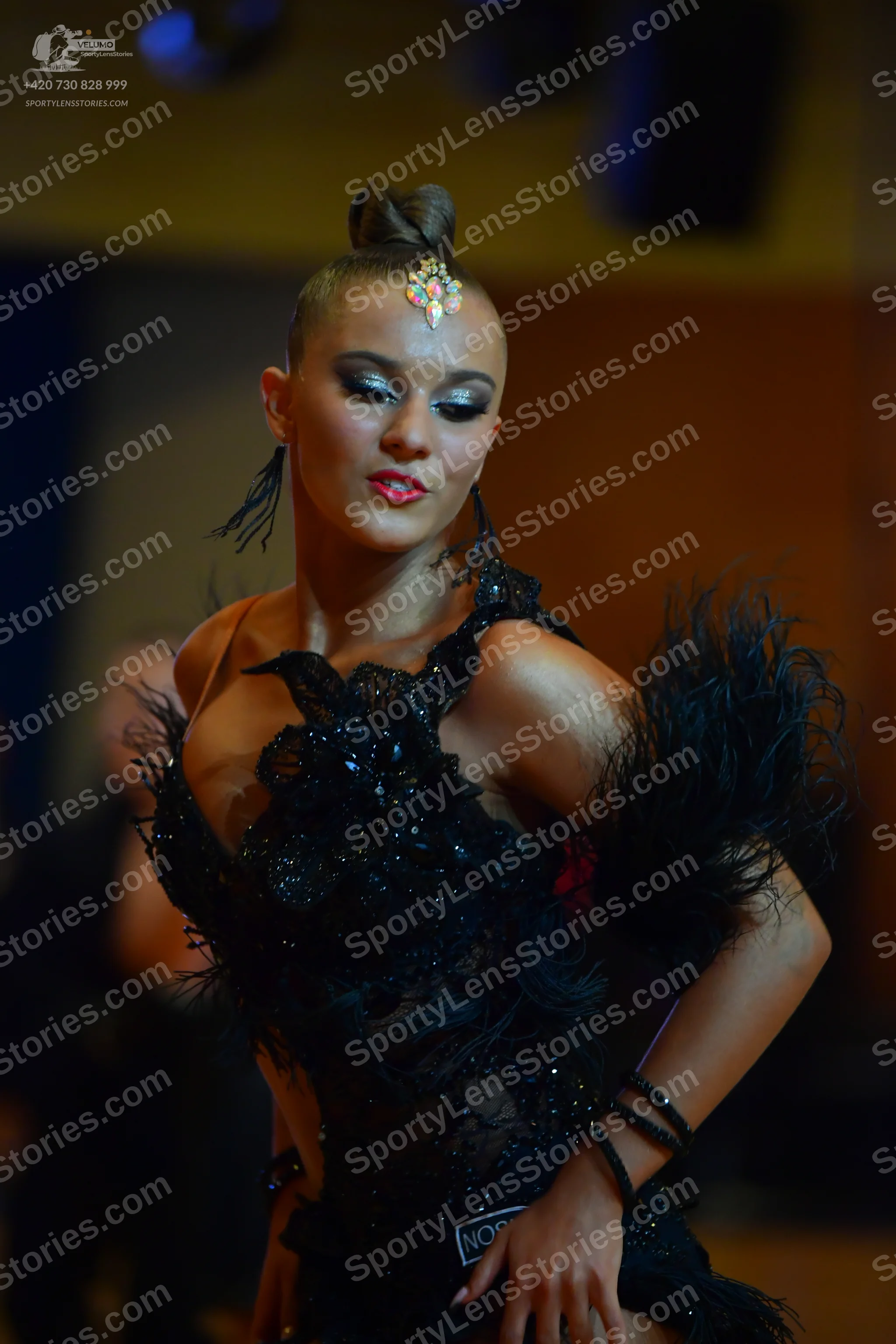 Dancesport competitor: Female dancer: black Latin dance dress with lace, sequins, and large black feath