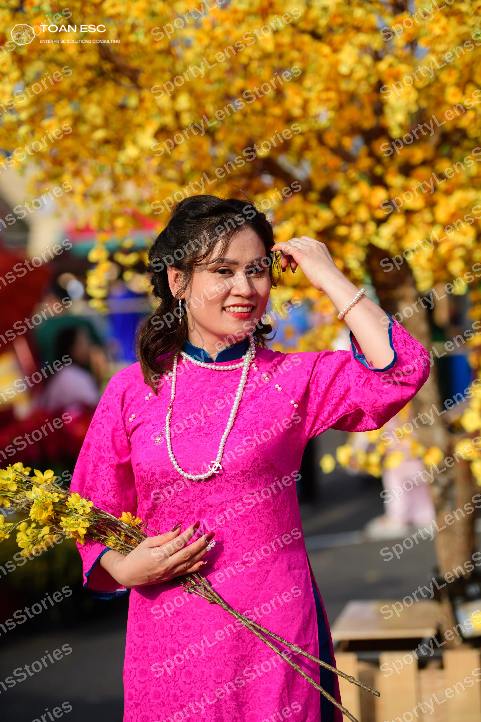 Dancesport competitor: Female dancer: pink long-sleeved Áo dài with a floral pattern and a pearl neckla