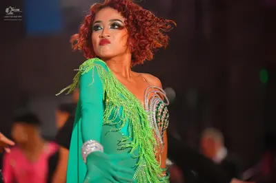 Dancesport competitor: Female dancer: Bright green Latin dress with long sleeves, fringe, and sequined 
