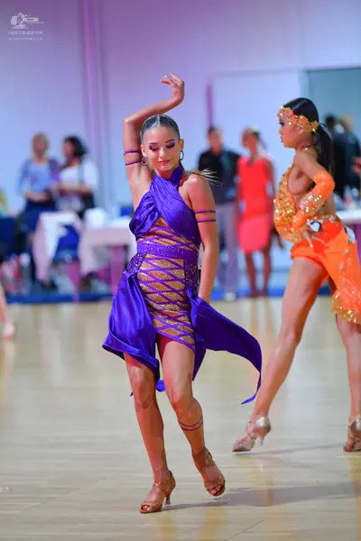 Dancesport competitor: Female dancer 1: purple latin dress with satin-like fabric and crisscross detail