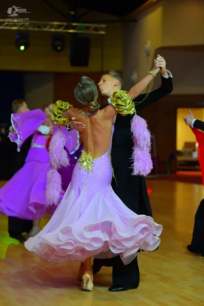 Dancesport competitor: Female dancer in foreground: light purple ballgown with a sequined bodice, a lar