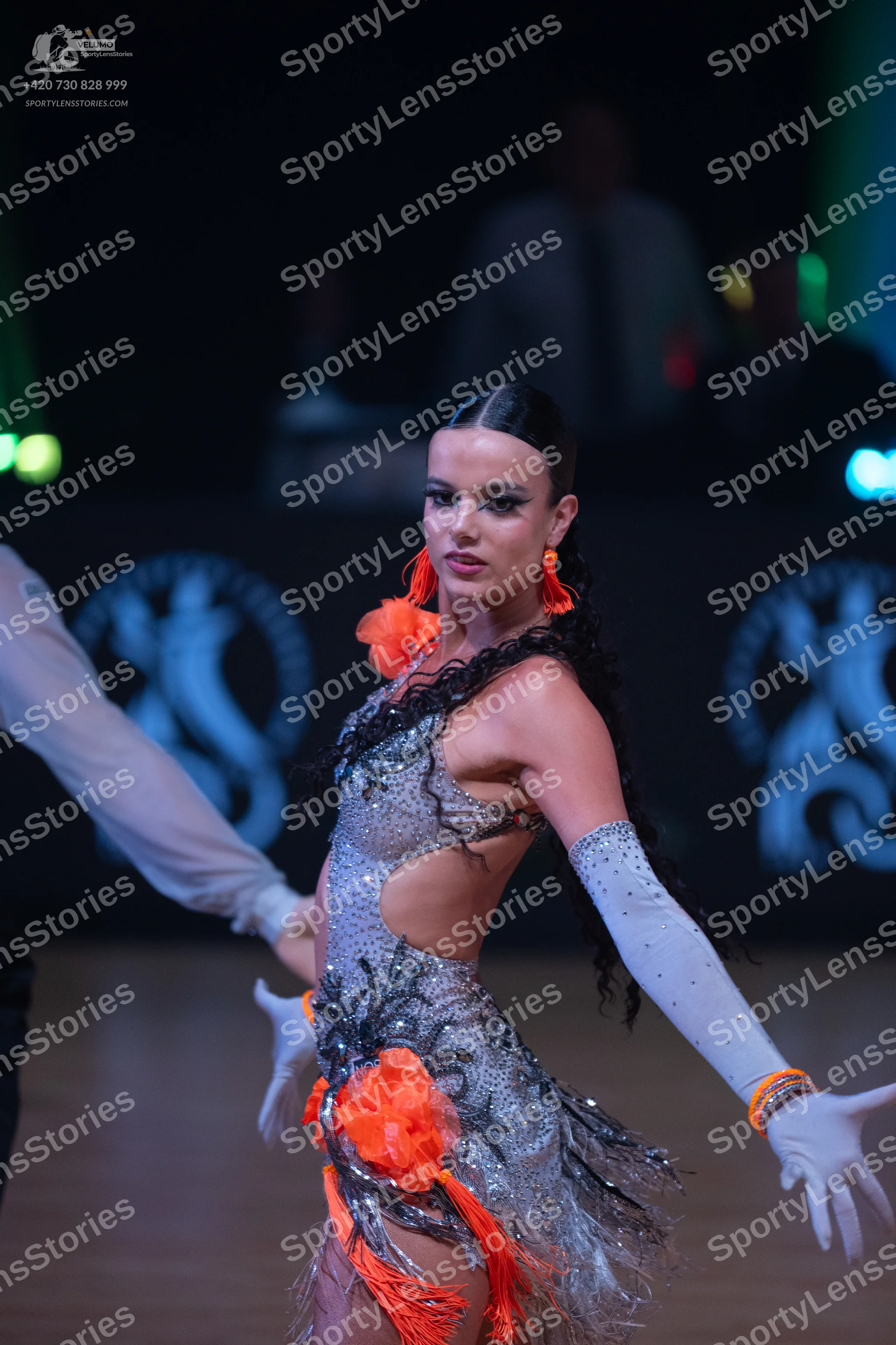 Dancesport competitor: Female dancer: silver sequined Latin dress with black feather-like fringe and br