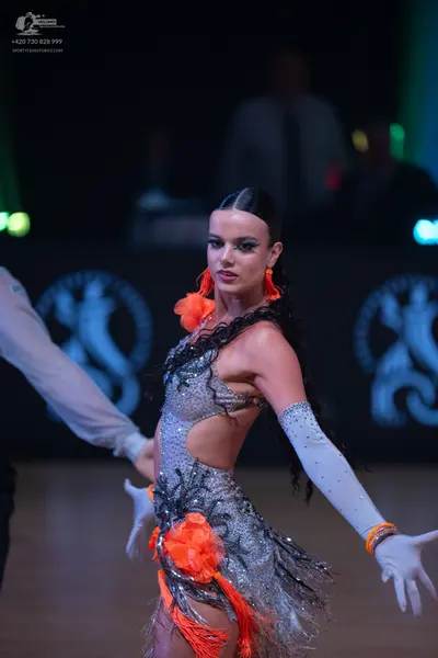 Dancesport competitor: Female dancer: silver sequined Latin dress with black feather-like fringe and br