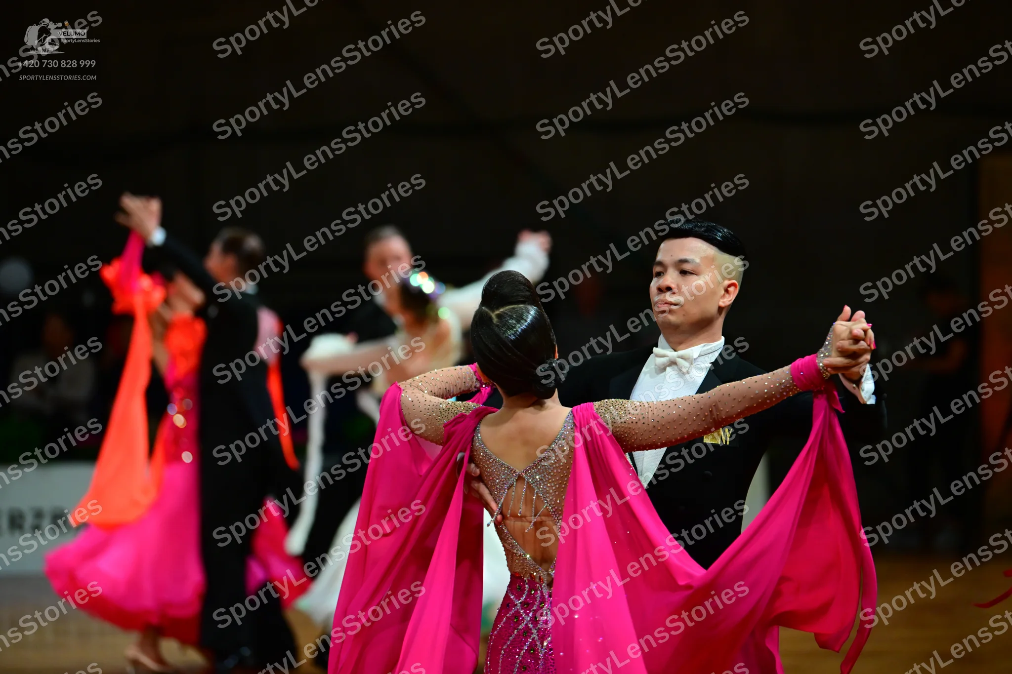 Dancesport competitor: Female dancer in foreground: pink latin dress with a sheer mesh back decorated w