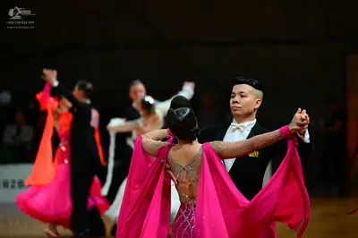 Dancesport competitor: Female dancer in foreground: pink latin dress with a sheer mesh back decorated w